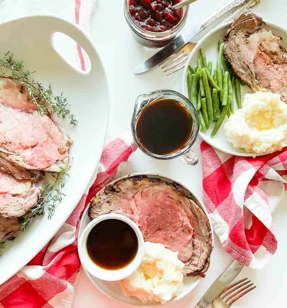 A plate of prime rib roast with gravy and green beans.