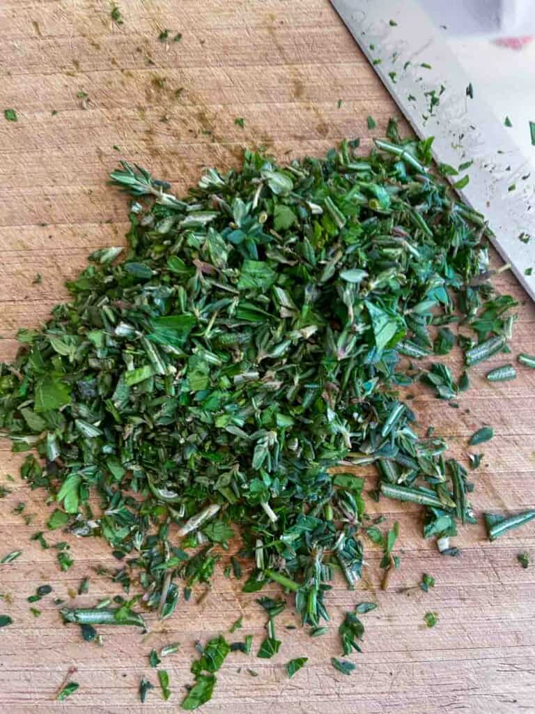 Chopped herbs on a cutting board for prime rib roast.