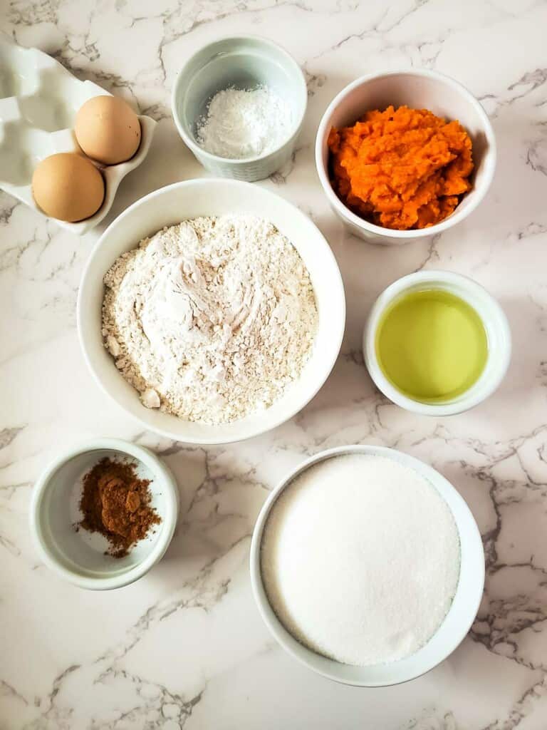 Ingredients for pumpkin muffins on a marble table.