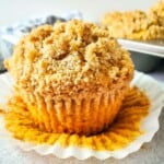 Pumpkin muffins with a crumb topping on a white plate.
