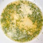 A white bowl with a mixture of herbs in it.