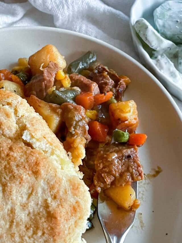A plate of stew and biscuits on a white plate.
