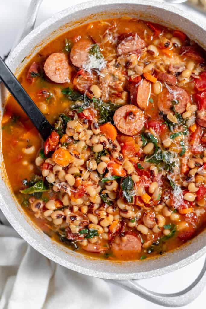 A pot of black eyed pea soup with sausage and spinach.