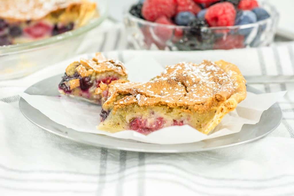 A slice of pie with berries on a plate.