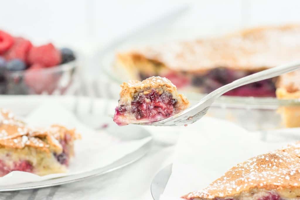 A slice of pie with berries and powdered sugar.