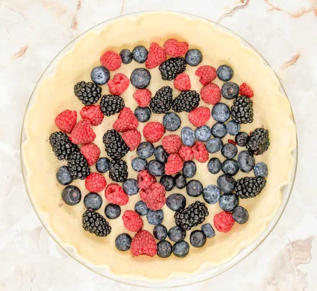 A pie crust filled with blueberries and raspberries.