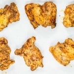 Four pieces of grilled chicken on a baking sheet.