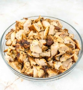 Shredded chicken in a glass bowl on a marble counter.