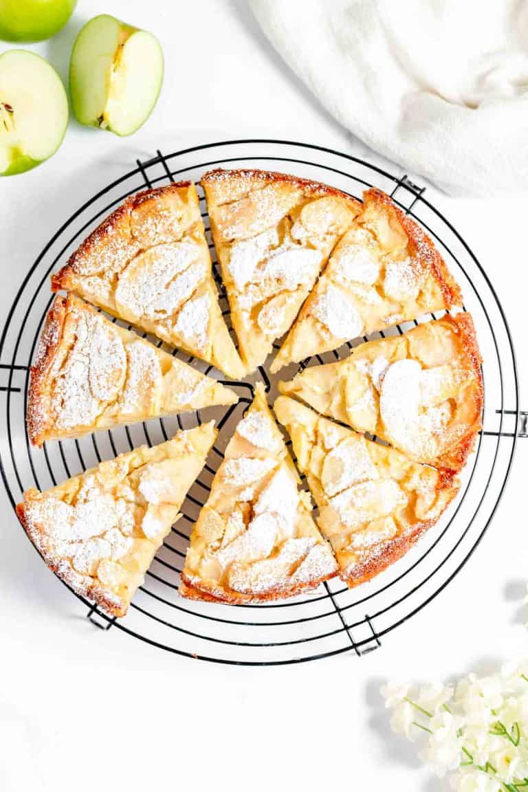 A slice of apple cake on a cooling rack.