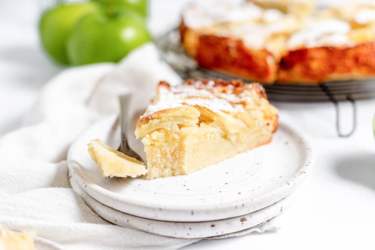 A slice of apple pie on a plate with a fork.