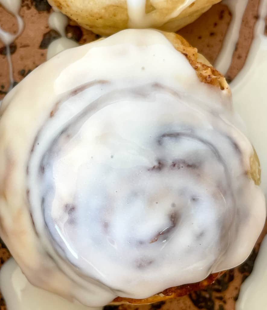 A plate of cinnamon rolls with icing on top.