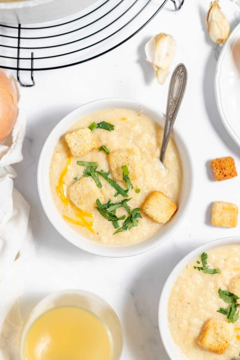 A bowl of soup with croutons and garlic.