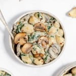 A bowl of pasta with mushrooms and spinach.