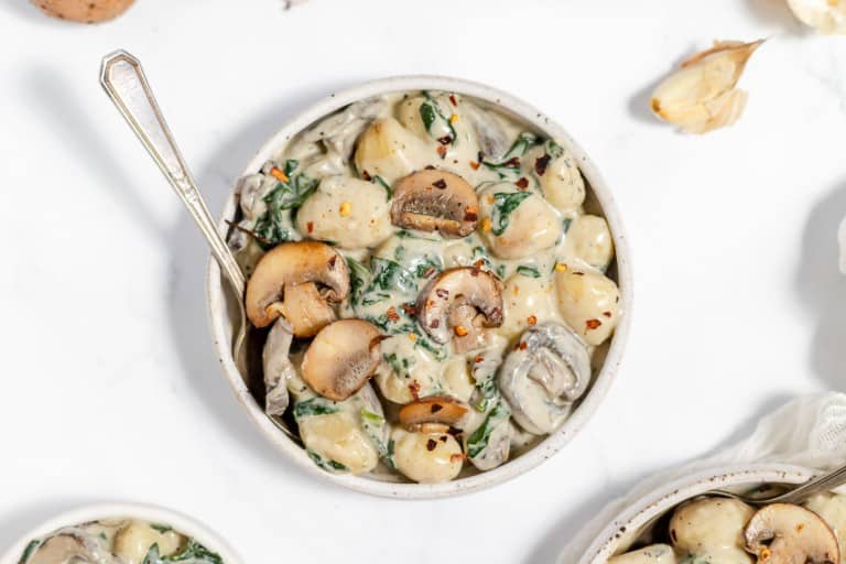 A bowl of pasta with mushrooms and spinach.