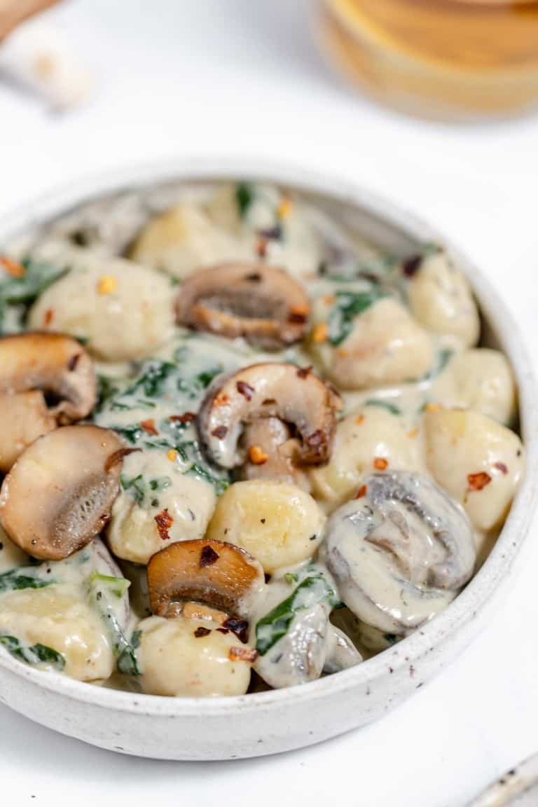 Mushroom and spinach dumplings in a white bowl.