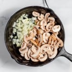 Mushrooms and onions in a cast iron skillet.