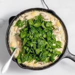 A cast iron skillet filled with spinach and mushrooms.