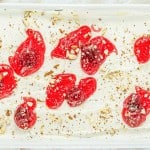 A white dish with red jelly and nuts on it.