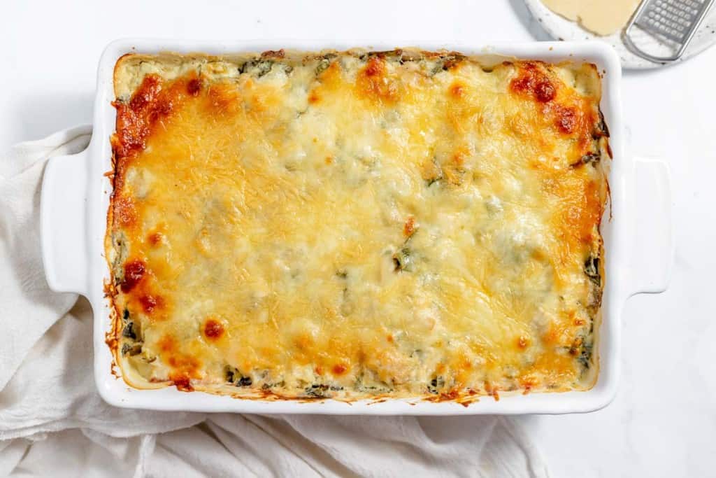 Cheesy spinach lasagna in a white dish.