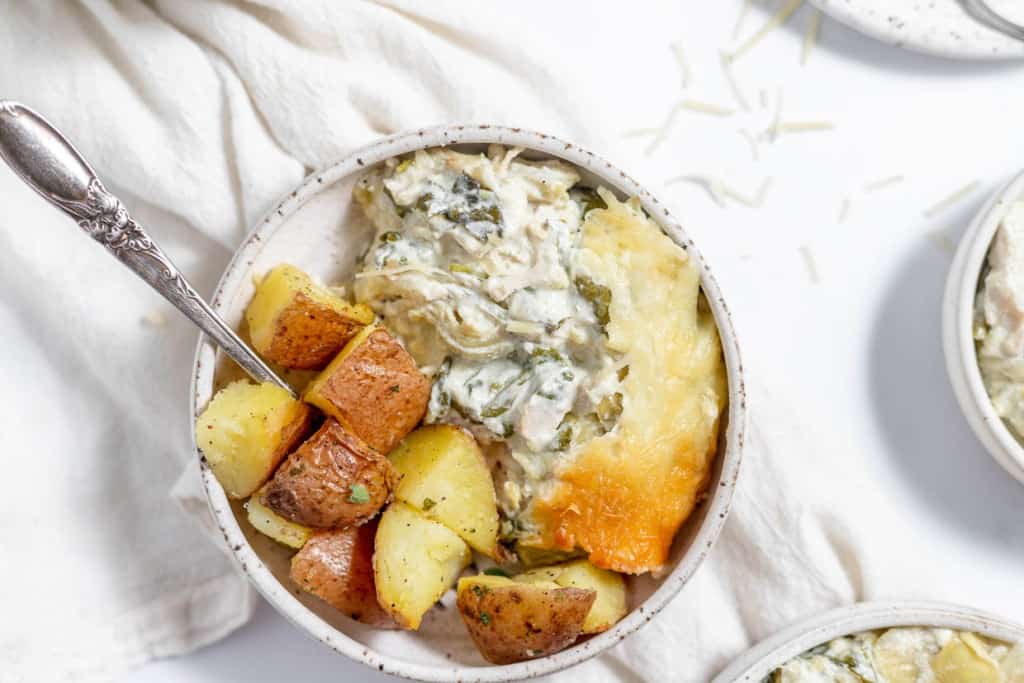 A bowl of chicken pot pie with potatoes and spinach.