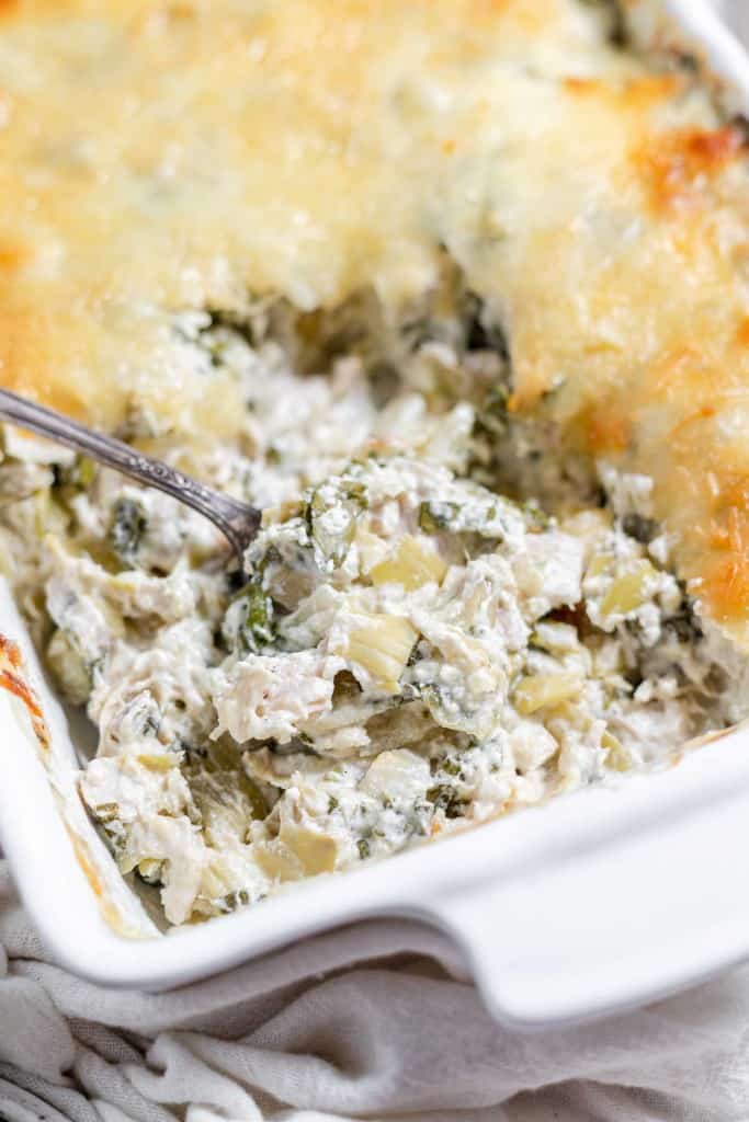 Chicken and spinach casserole in a white dish with a fork.