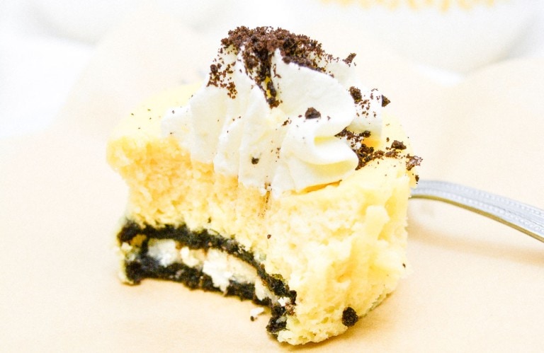 A slice of mini cookies and cream cheesecakes on a paper napkin with a fork.