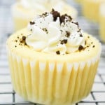 A close-up of mini cookies and cream cheesecakes with cookie crumbles on top, placed in a yellow paper liner.