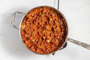 A pot of cooked meat sauce with diced vegetables on a white countertop.