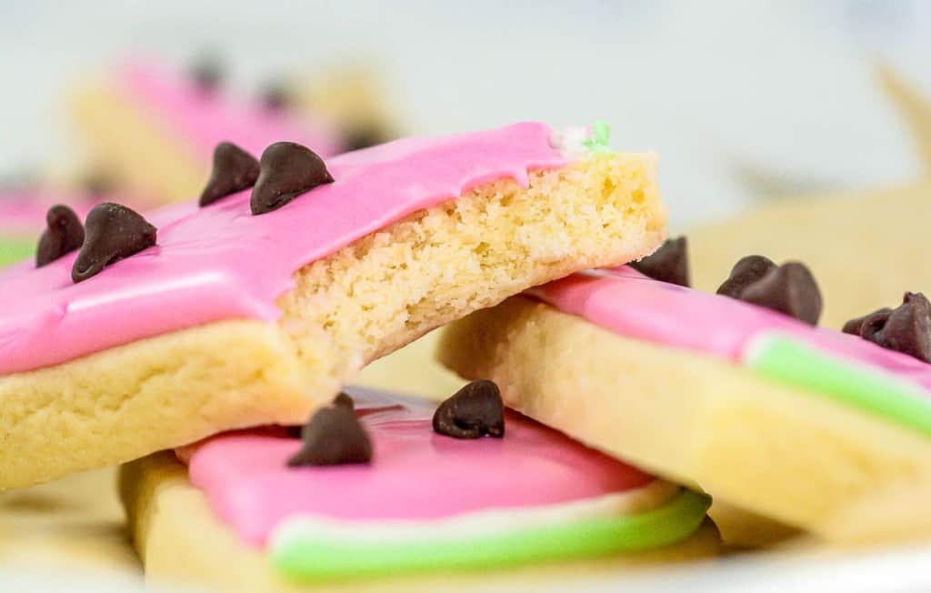 Sugar cookies with pink frosting and chocolate chips.