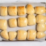 A tray of freshly baked, golden-brown copycat Texas Roadhouse rolls arranged on parchment paper.