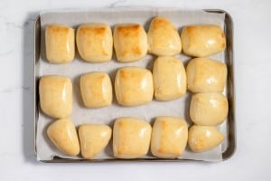 A tray of freshly baked, golden-brown copycat Texas Roadhouse rolls arranged on parchment paper.