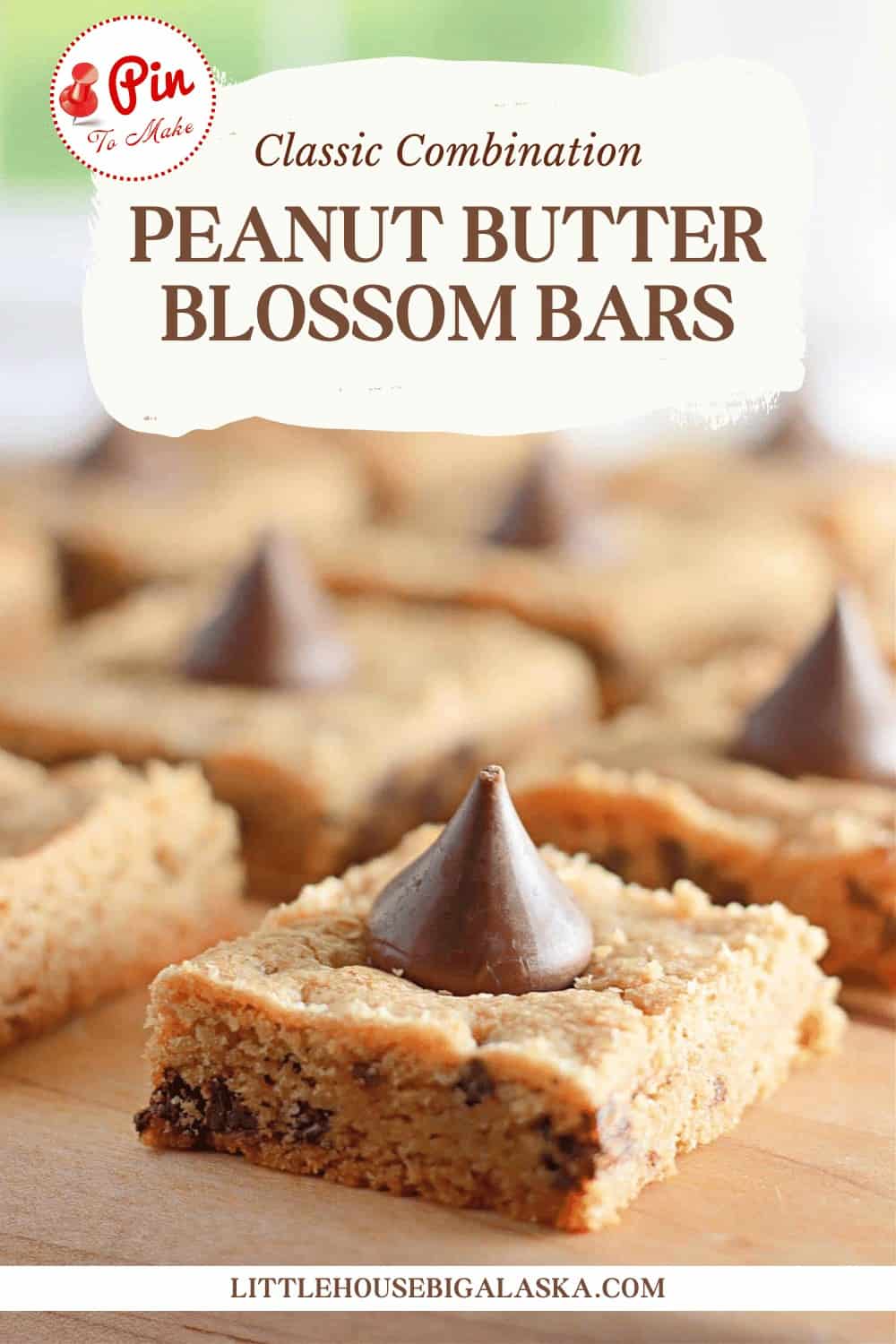 Peanut butter blossom bars on a wooden surface with a chocolate kiss on top.