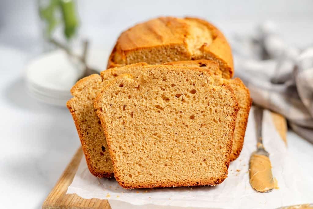 Sliced peanut butter bread on a white surface with a knife and cloth in the background.