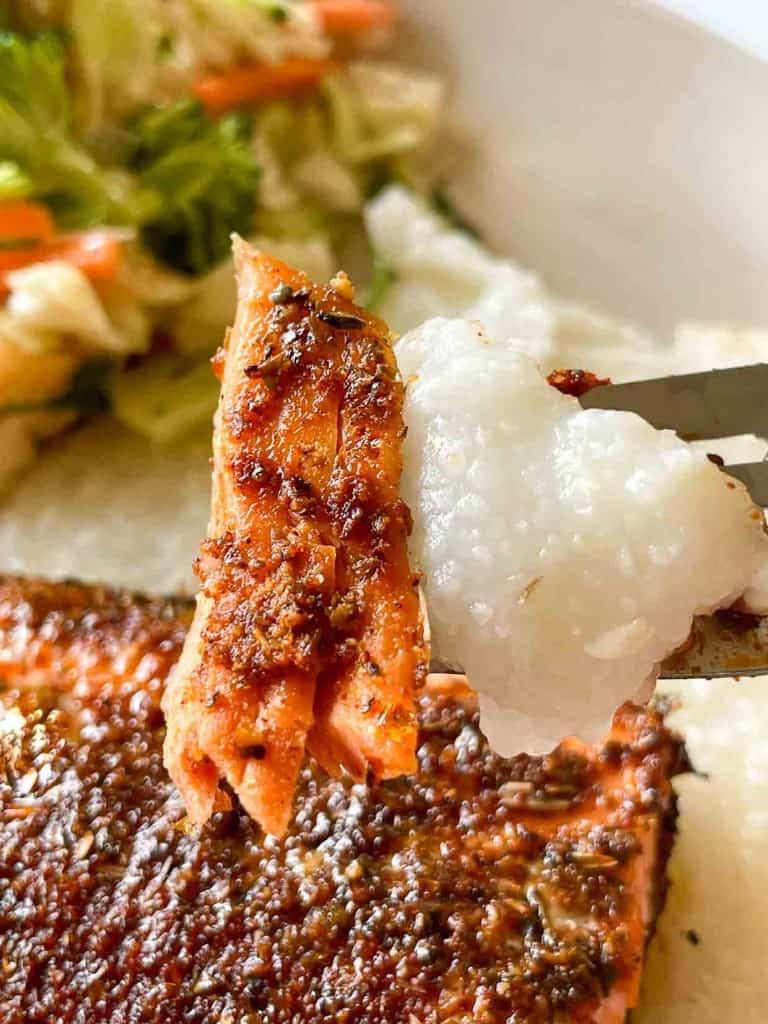 Close-up of a plate with grilled salmon, white rice, and mixed vegetables.