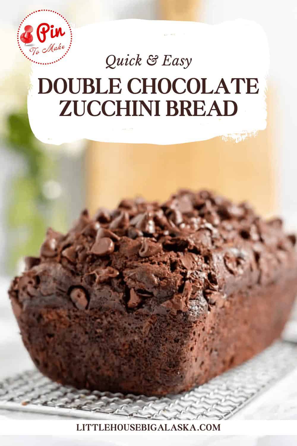 Close-up of a loaf of double chocolate zucchini bread on a cooling rack, with text that reads "Quick & Easy Double Chocolate Zucchini Bread" and "littlehousebigalaska.com" in the background.