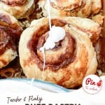 A close-up of puff pastry cinnamon rolls being drizzled with icing. The rolls are labeled as "Tender & Flaky Puff Pastry Cinnamon Rolls." The text at the bottom reads "littlehousebigalaska.com.