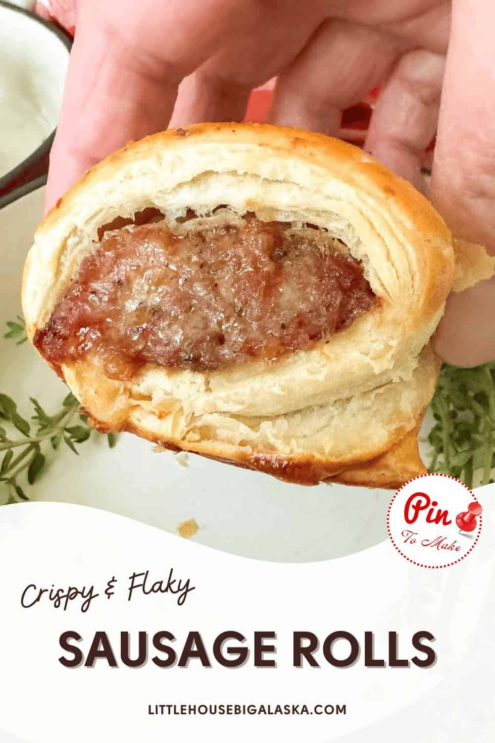 A hand holding a half-eaten sausage roll with a crispy and flaky pastry. Text reads "Crispy & Flaky Sausage Rolls" and "LITTLEHOUSEBIGALASKA.COM.