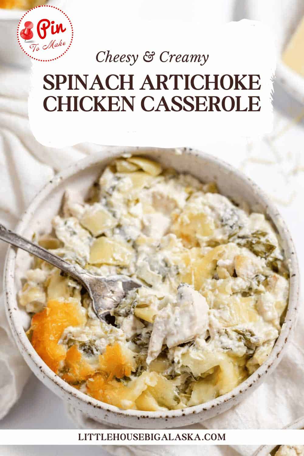 A bowl of creamy spinach artichoke chicken casserole, topped with a golden crust, placed on a white tablecloth. The dish is labeled "Cheesy & Creamy Spinach Artichoke Chicken Casserole.