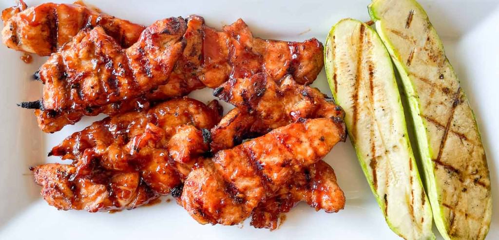 Our BBQ Favorites feature grilled barbecue chicken skewers and grilled zucchini slices served on a white plate.