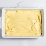A rectangular white baking dish filled with smooth, creamy yellow batter, placed on a light marble countertop.