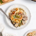 A plate of a baked dish featuring meat, green peppers, and mushrooms in a creamy sauce, with a fork rested on the side.