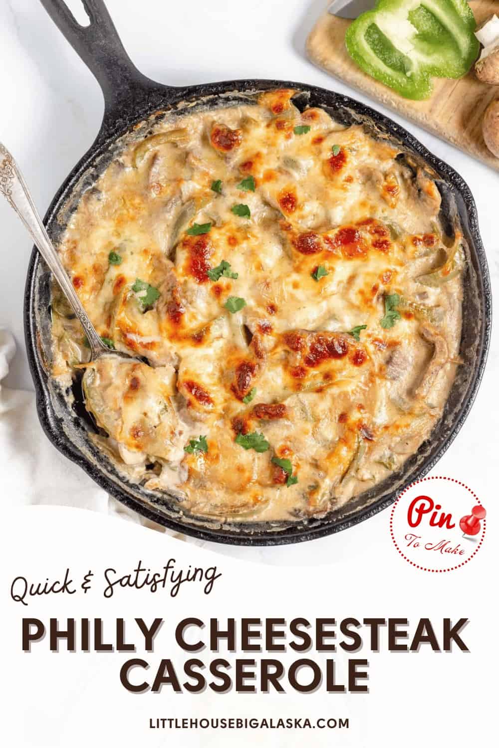 Iron skillet filled with cheesy Philly Cheesesteak casserole. Text overlay reads, "Quick & Satisfying Philly Cheesesteak Casserole." Website link at the bottom: littlehousebigalaska.com.