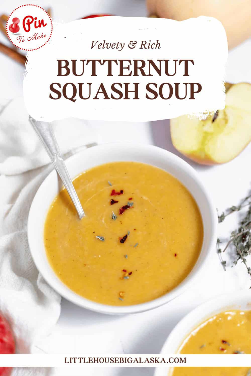 A bowl of butternut squash soup garnished with herbs, placed on a white tablecloth next to a sliced apple. The text reads, "Velvety & Rich Butternut Squash Soup.