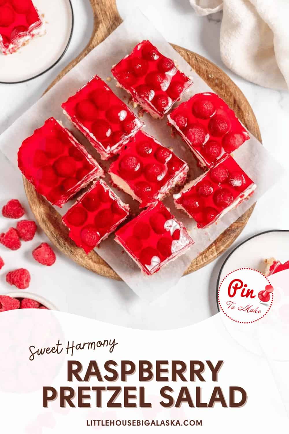 Overhead view of raspberry pretzel salad squares on a plate and parchment paper, surrounded by fresh raspberries and whipped cream. Text reads "Sweet Harmony Raspberry Pretzel Salad.
