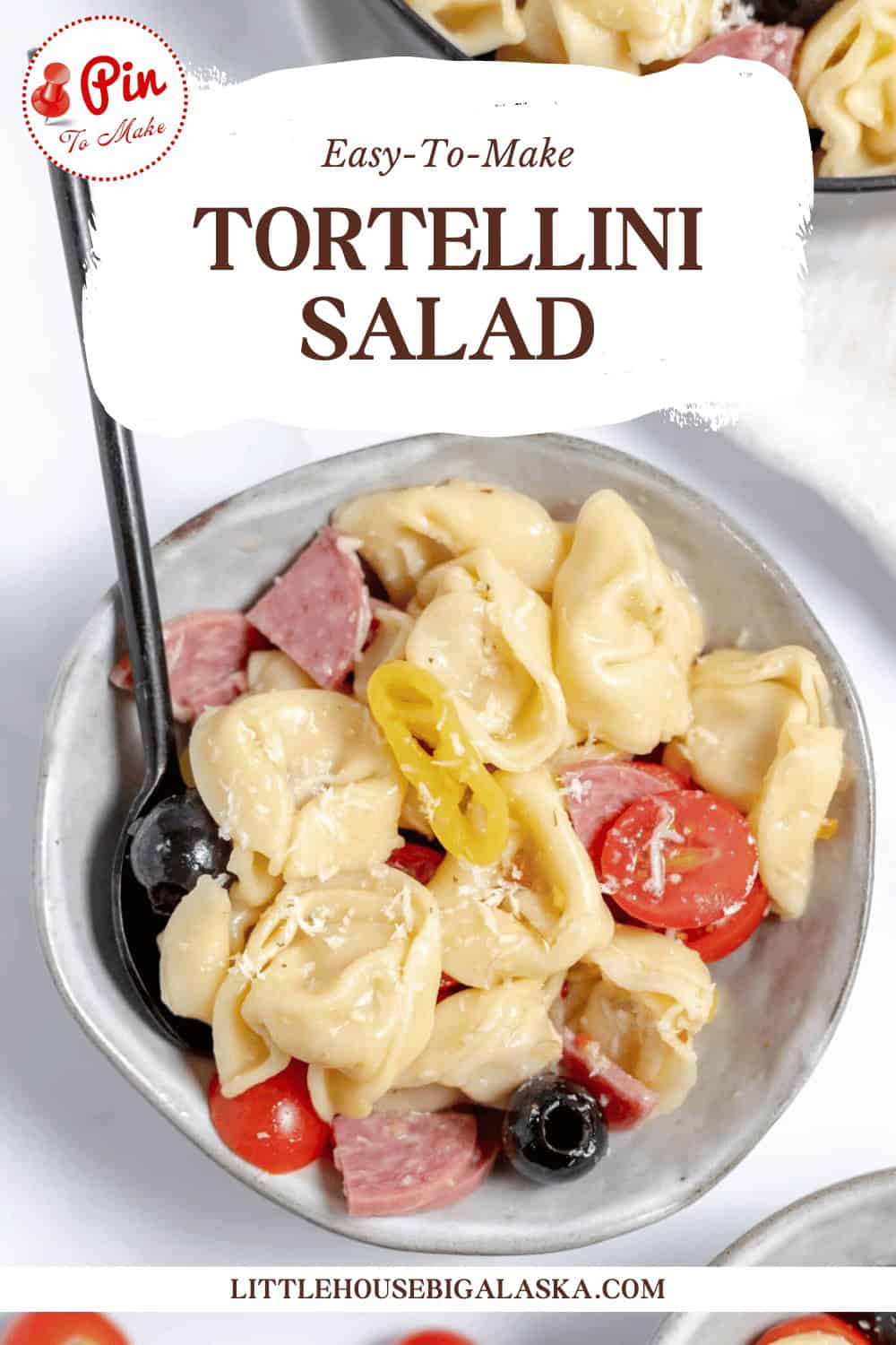 A bowl of tortellini salad with olives, cherry tomatoes, cheese, and meat slices. The text above reads, "Easy-To-Make TORTELLINI SALAD." The website "LITTLEHOUSEBIGALASKA.COM" is visible at the bottom.
