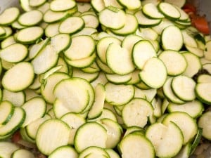 Sliced green zucchini arranged in a pile, showcasing their circular cross-sections and light seedy flesh, perfect for an Unstuffed Zucchini Casserole.