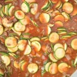 A pot filled with an unstuffed zucchini casserole and meat stew, featuring sliced zucchini, chunks of meat, and vegetables in a tomato-based sauce.