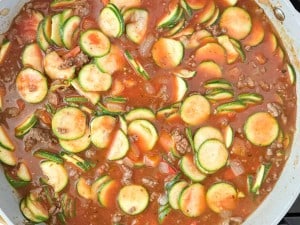 A pot filled with an unstuffed zucchini casserole and meat stew, featuring sliced zucchini, chunks of meat, and vegetables in a tomato-based sauce.