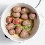 A pot of small whole potatoes cooking with a herb and spice mixture.