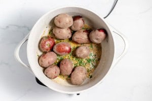 A pot of small whole potatoes cooking with a herb and spice mixture.